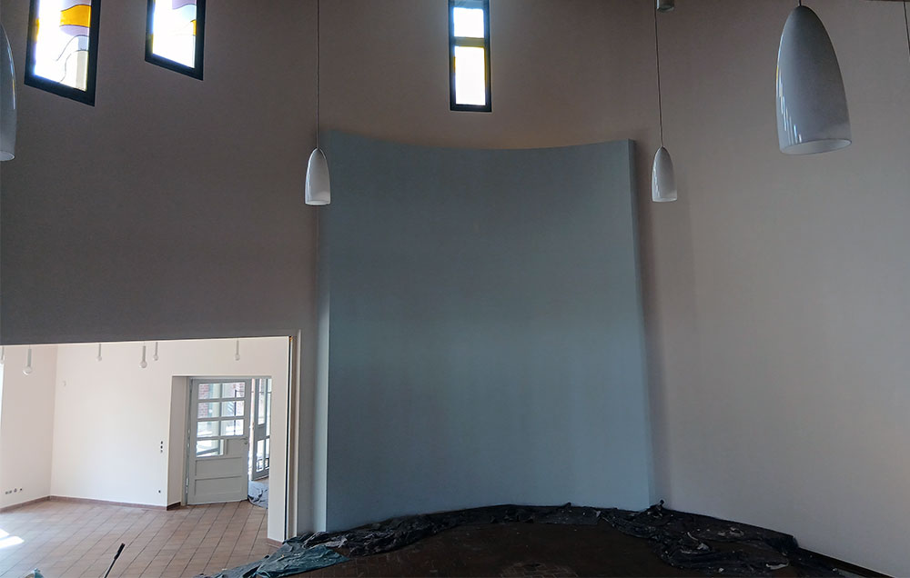 Hoher Innenraum mit heller Wandgestaltung und akzentuierter Mittelwand