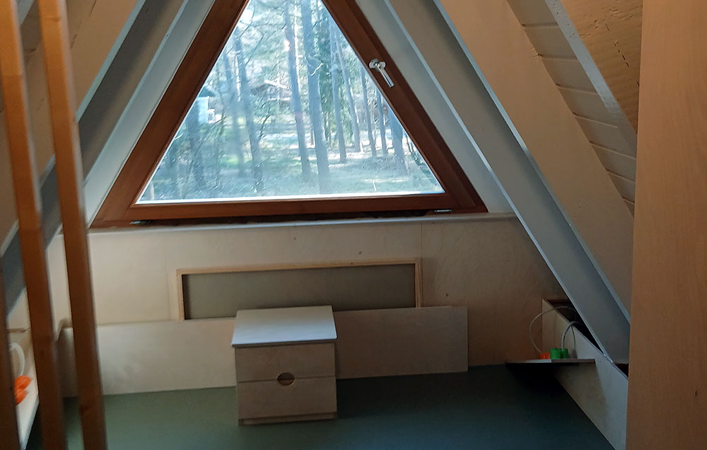 Dachraum mit dreieckigem Fenster und heller Innenverkleidung
